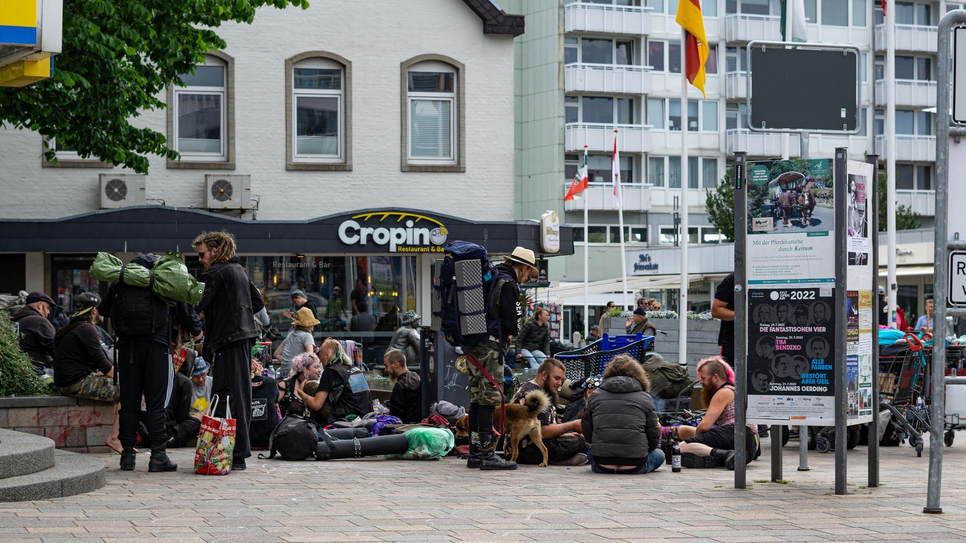 In der Innenstadt von Westerland auf Sylt sitzen viele Punks. Sie haben Rücksäcke und Hunde bei sich.