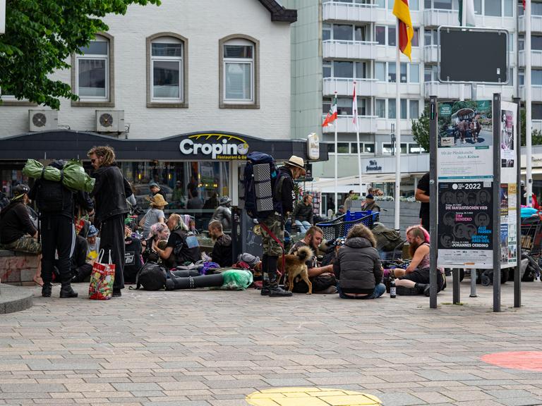 In der Innenstadt von Westerland auf Sylt sitzen viele Punks. Sie haben Rücksäcke und Hunde bei sich.
