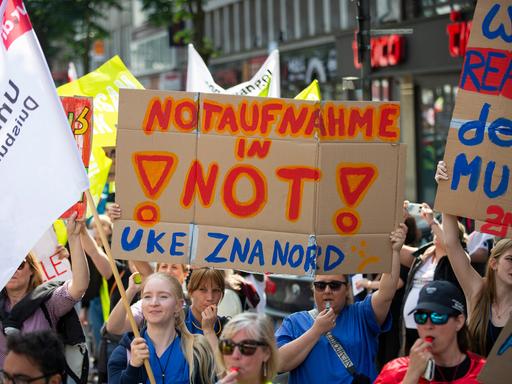 Demonstrantinnen tragen ein Schild mit der Aufschrift "Notaufnahme in Not! UKE ZNA Nord". Zahlreiche Demonstranten aus dem Gesundheitsbereich ziehen durch die Düsseldorfer Innenstadt in Richtung Nordrhein-Westfälischer Landtag. Die Gewerkschaft Verdi hatte zur Demonstration für Unikliniken unter dem Motto "Wir für Euch, ihr für uns" aufgerufen.