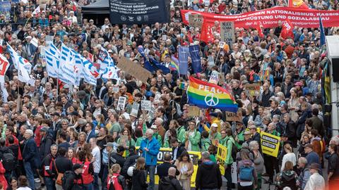 Blick in eine große Menschenmenge bei einer Demonstration in Hamburg. Zu sehen sind viele Fahnen und ein großes rotes Banner. 