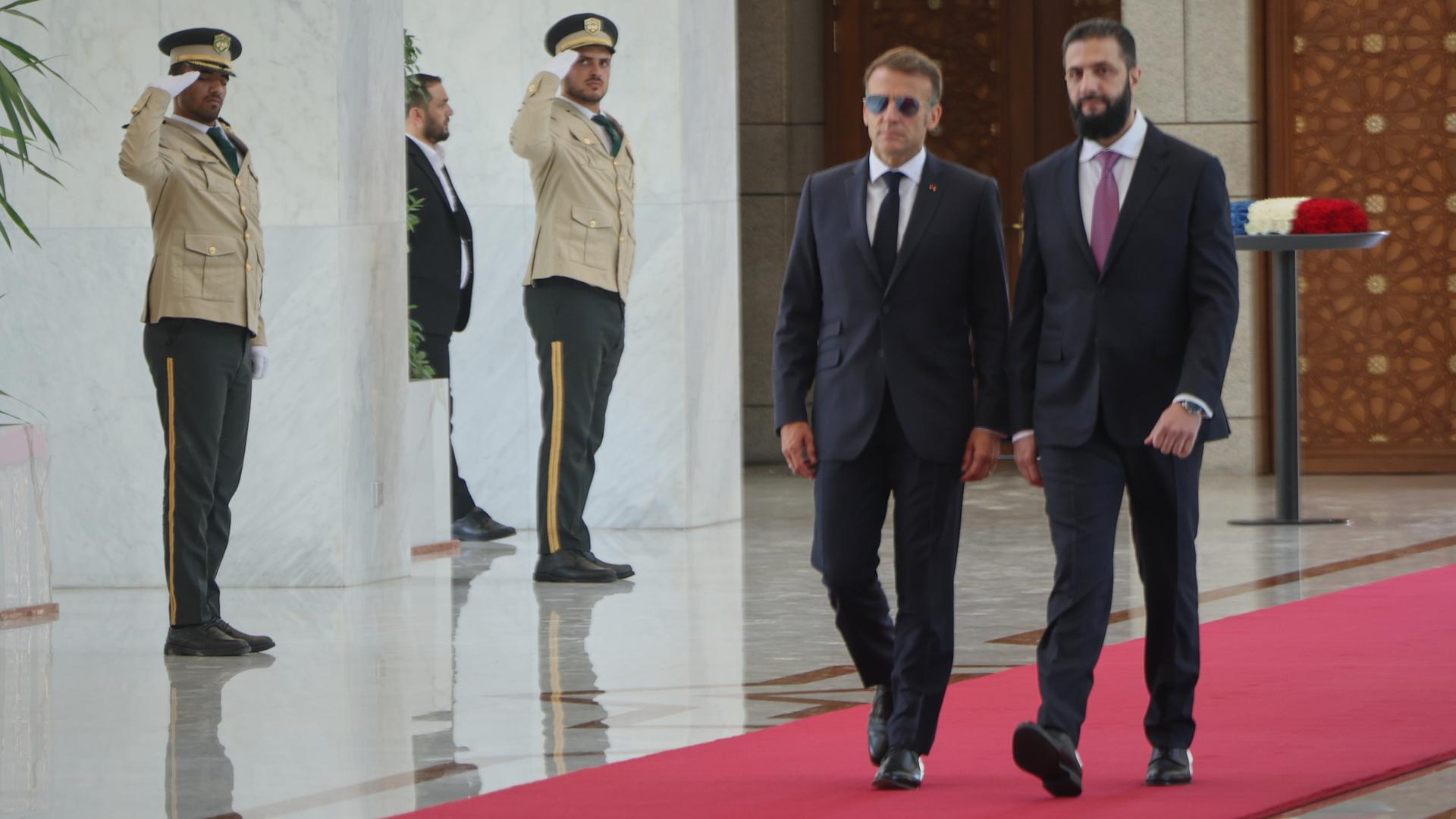 Damaskus: Der syrische Präsident Ahmed al-Scharaa (r) trifft im Präsidentenpalast auf den französischen Präsidenten Emmanuel Macron. Sie gehen nebeneinander auf einem roten Teppich.