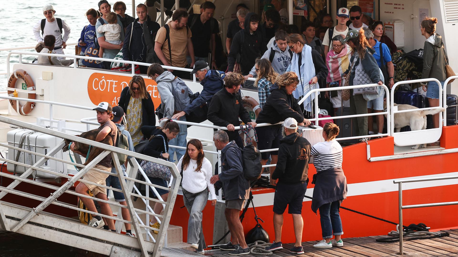 Viele Menschen verlassen gerade ein Passagierschiff und gehen über eine Landungsbrücke. 
