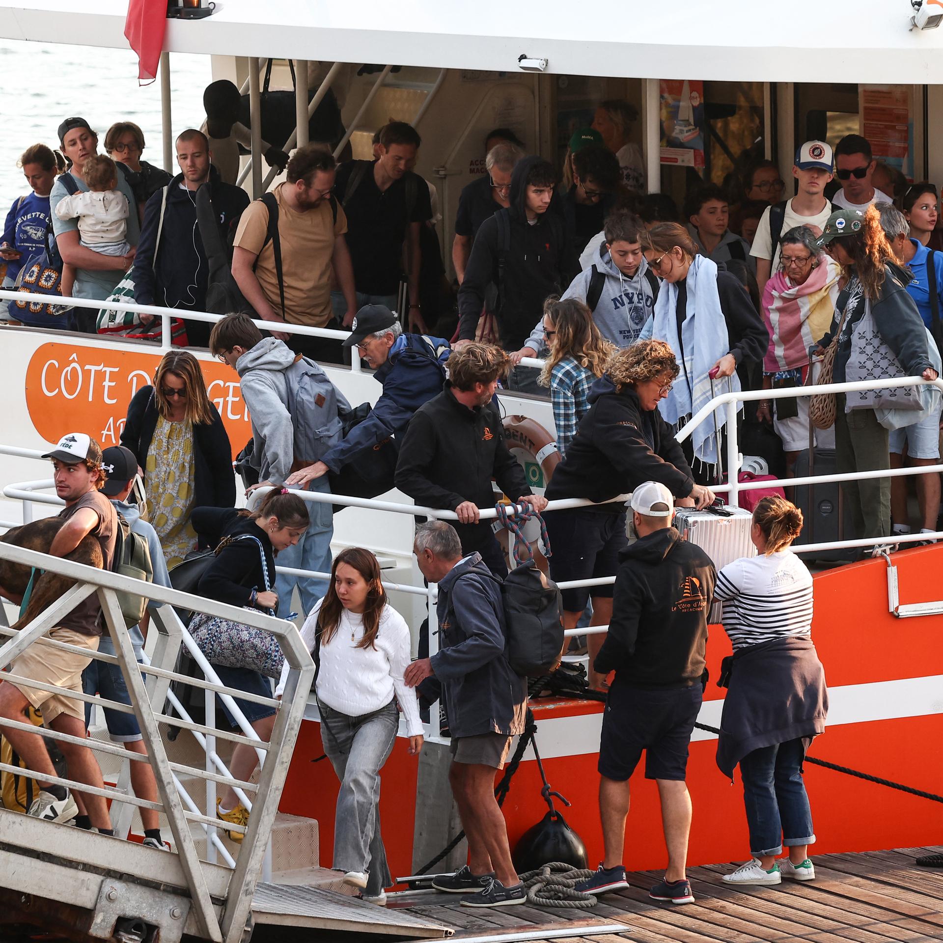 Viele Menschen verlassen gerade ein Passagierschiff und gehen über eine Landungsbrücke. 