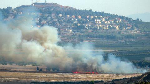 Rauch steigt von einem Feuer im Süden des Libanon auf. Im Hintergrund ein Hügel mit zahlreichen Häusern.