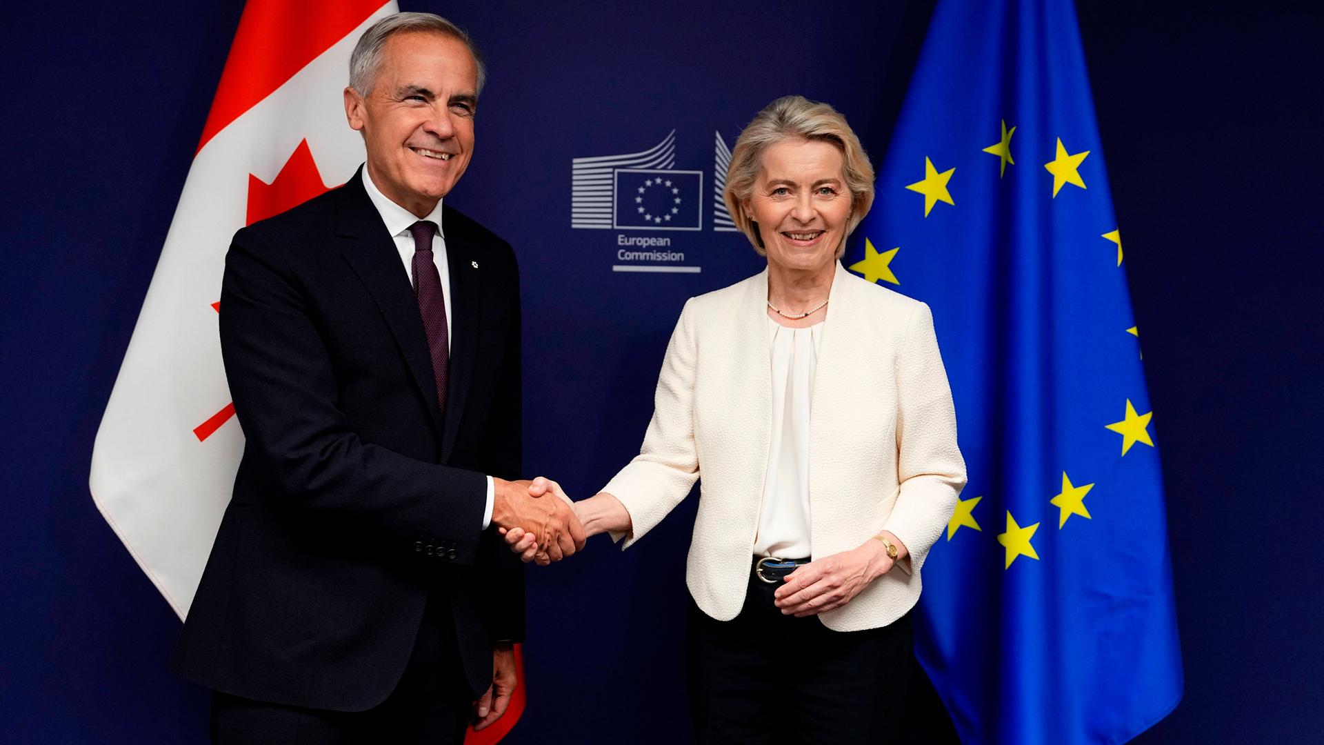 Mark Carney und Ursula von der Leyen schütteln Hände vor Flaggen von Kanada und der EU.