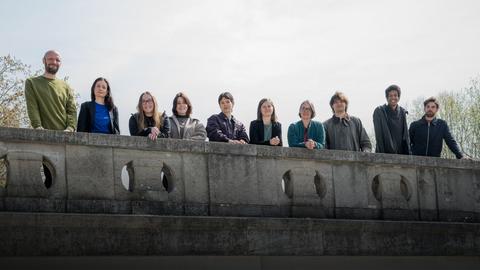 Eine Gruppe von Männern und Frauen, die auf einer steinernen Brücke stehen und hinunterschauen
