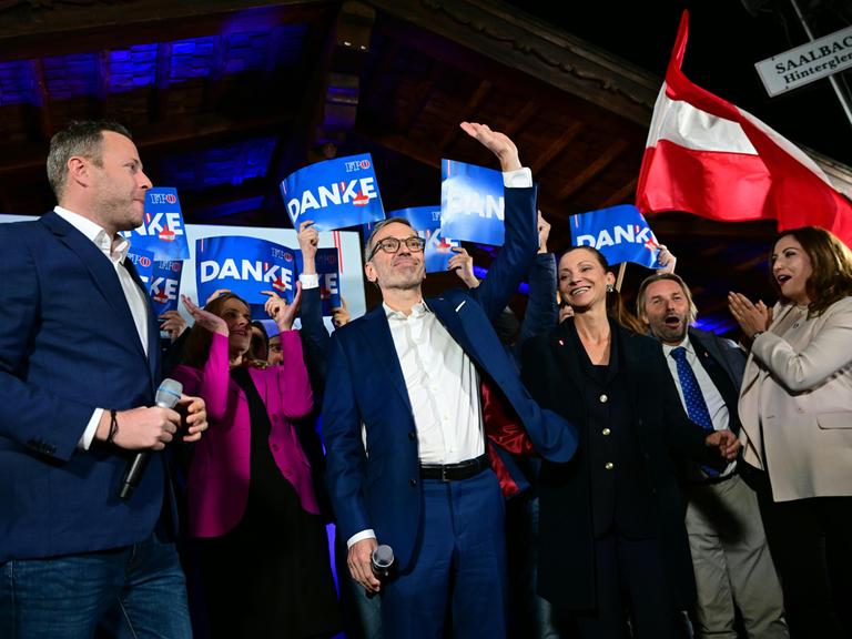 Die Politiker der rechtspopulistischen FPÖ Michael Schnedlitz, Herbert Kickl und Susanne Fürst feiern mit erhobenen Händen und Österreich-Flaggen im Hintergrund ihren Wahlerfolg bei der Nationalratswahl in Wien. 