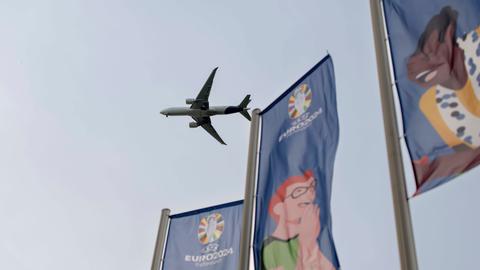 Ein Flugzeug im Landeanflug auf den Frankfurter Flughafen, vorne wehen EURO-2024-Flaggen.