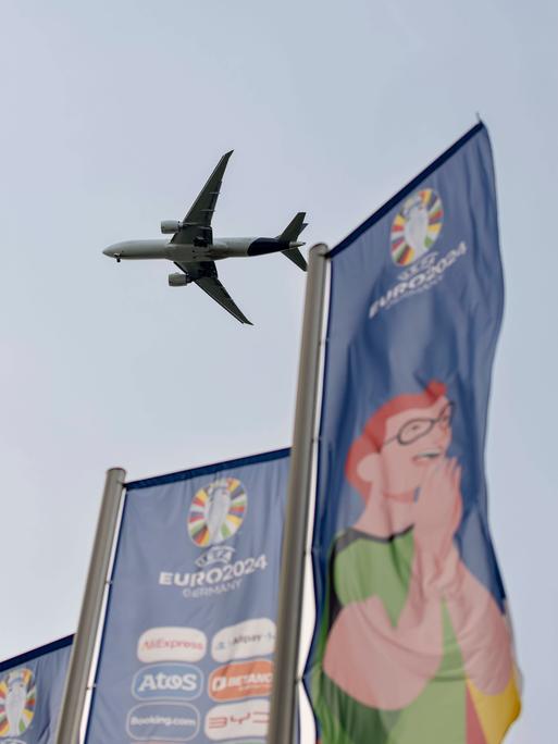 Ein Flugzeug im Landeanflug auf den Frankfurter Flughafen, vorne wehen EURO-2024-Flaggen.