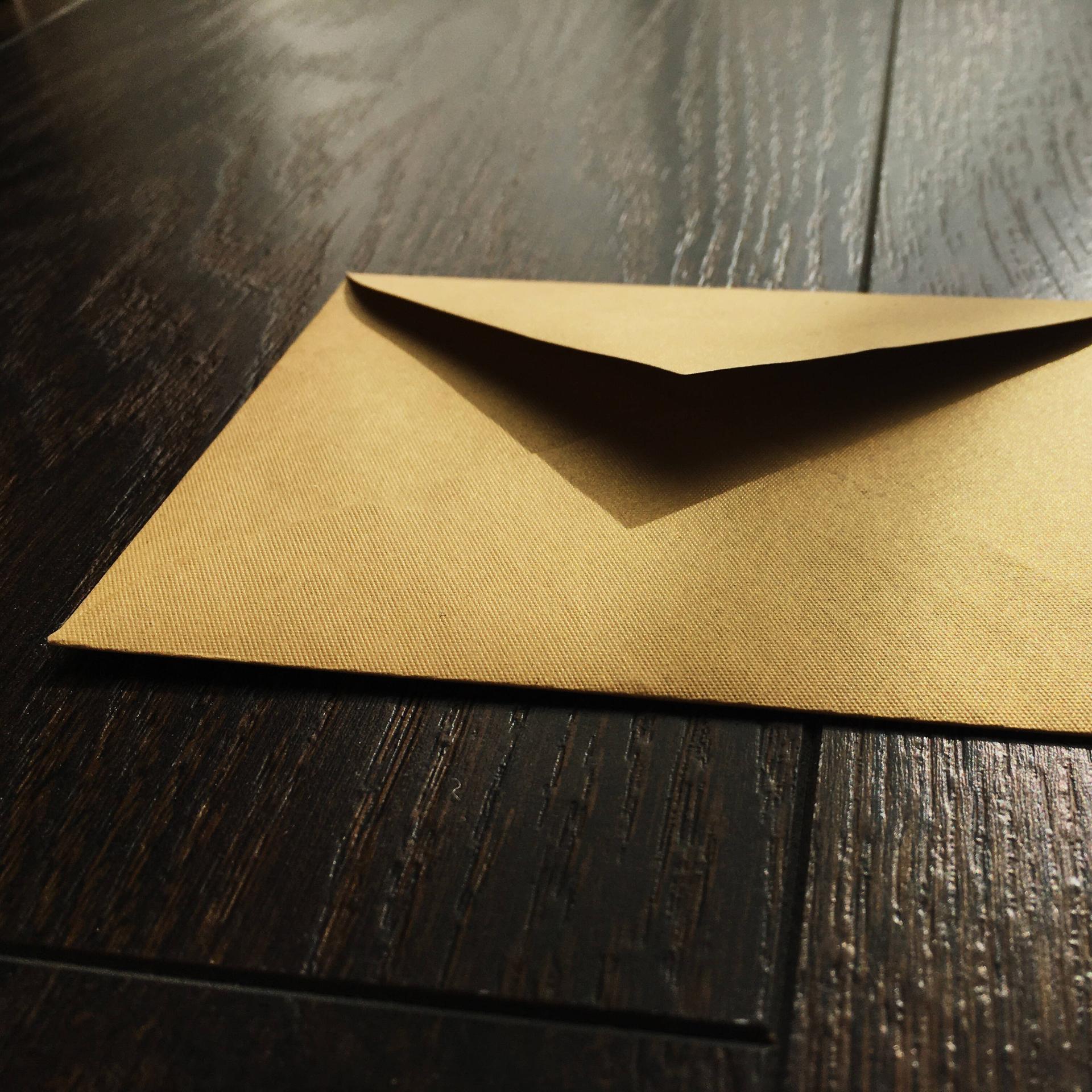 Ein goldener Briefumschlag liegt auf einer Fläche aus Holz.
