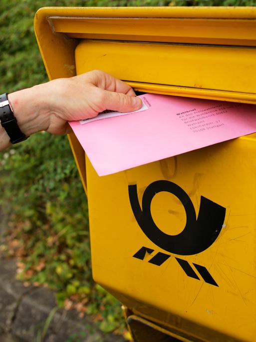 Ein Wahlbrief wird in einen Briefkasten der Deutschen Post gesteckt.