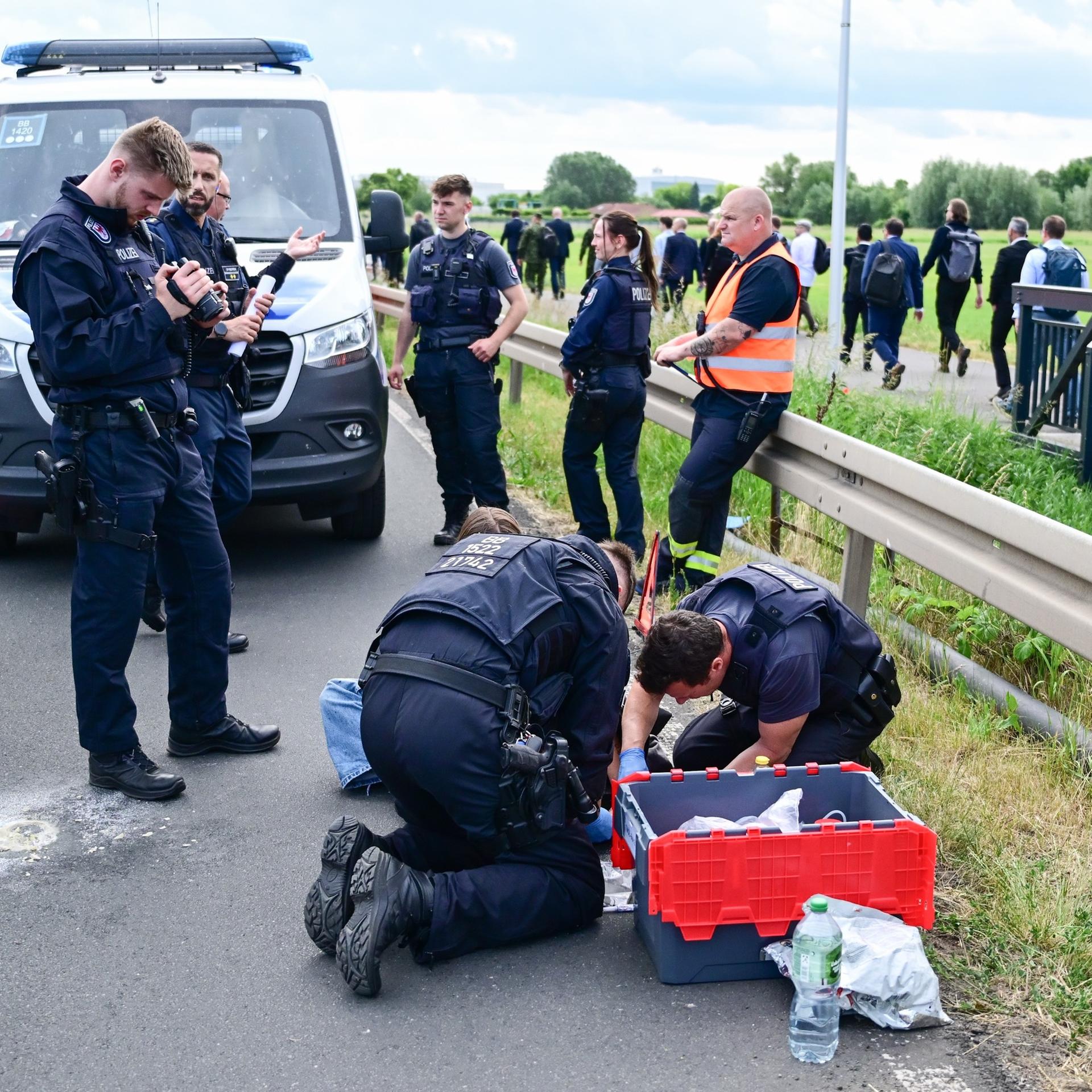 Berlin-Schönefeld: Polizeibeamte lösen während der Internationalen Luft- und Raumfahrtausstellung (ILA) auf dem Berlin ExpoCenter Airport an einer Zufahrtsstraße eine festgeklebte Person. 