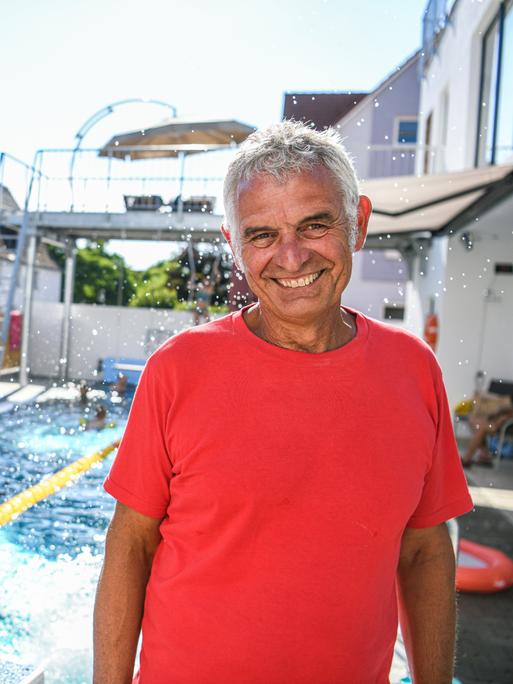 Achim Gall steht mit einem breiten Lächeln vor seinem Schwimmbecken.