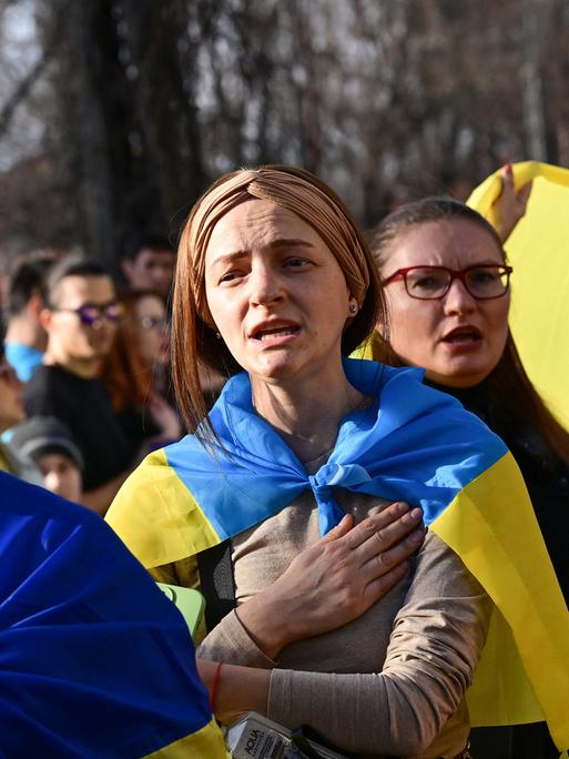 Ukrainische Frauen singen während einer Demonstration vor der russischen Botschaft in Bukarest, Rumänien, anlässlich des zweijährigen Krieges seit dem Einmarsch Russlands in die Ukraine.