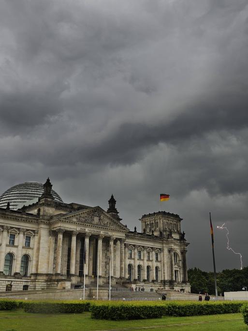Das Berliner Reichstagsgebäude vor dunkelen Wolken eines Unwetters.
