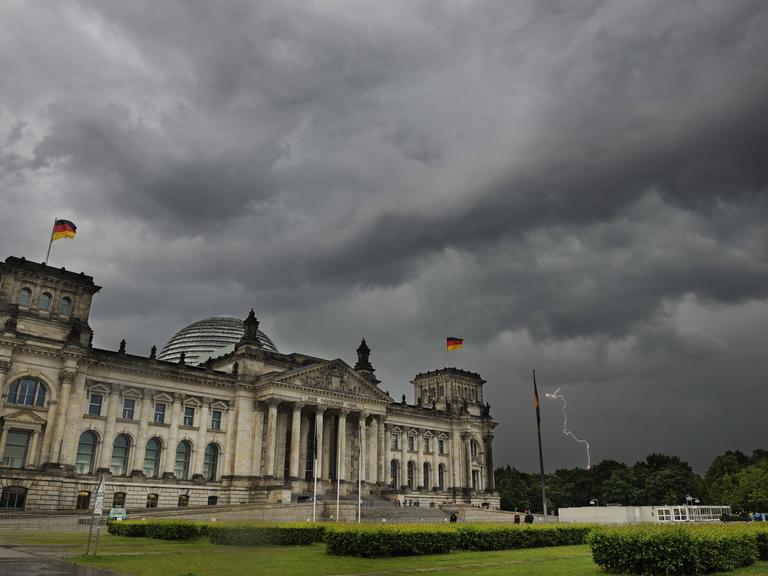Das Berliner Reichstagsgebäude vor dunkelen Wolken eines Unwetters.