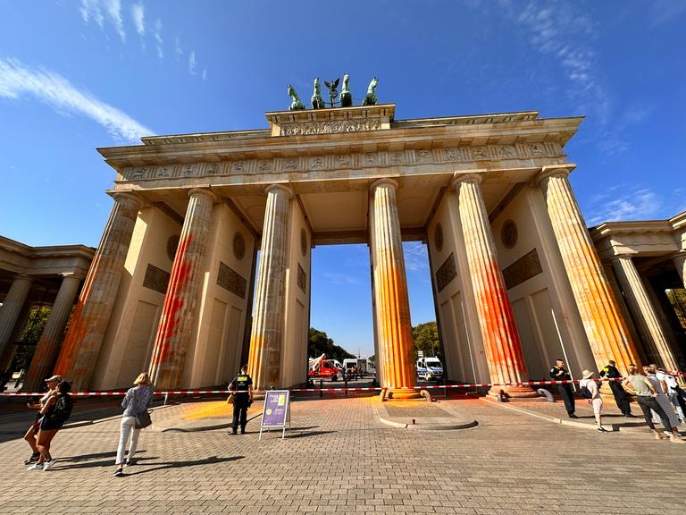 Die Säulen des Brandenburger Tores in Berlin mit Farbe besprüht. Der Bereich vor dem Tor ist abgesperrt. 