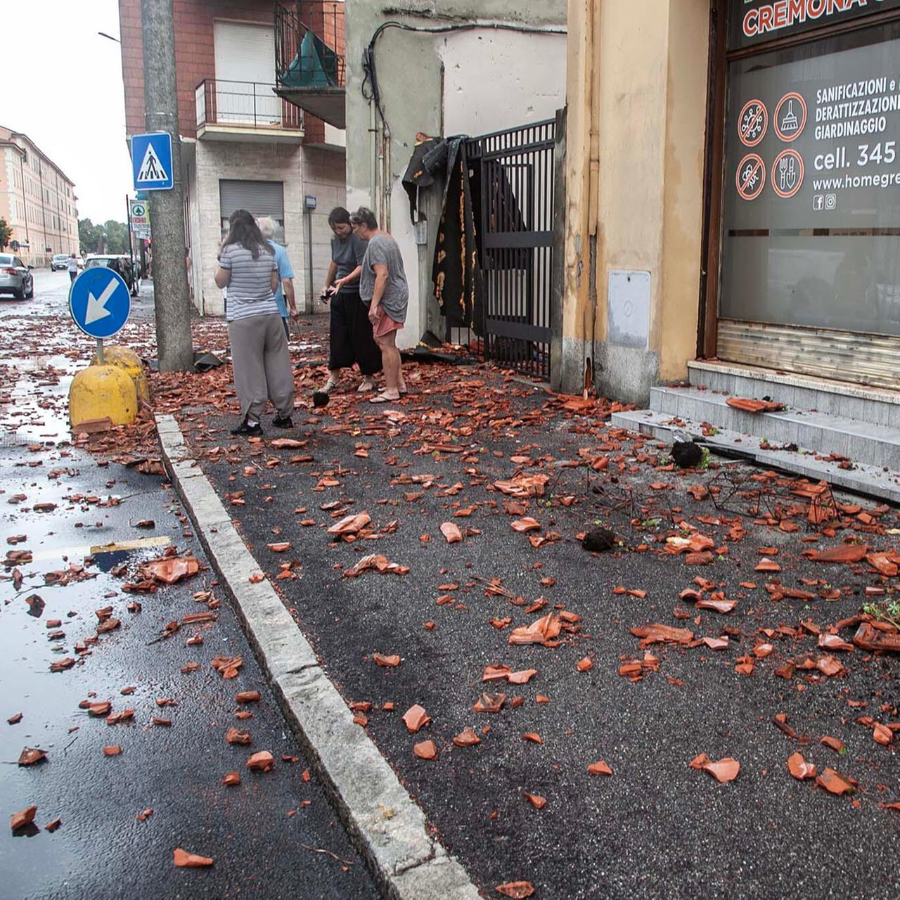 Cremona, Norditalien: Menschen stehen am Rand einer Straße zwischen zertrümmerten Dachziegeln.