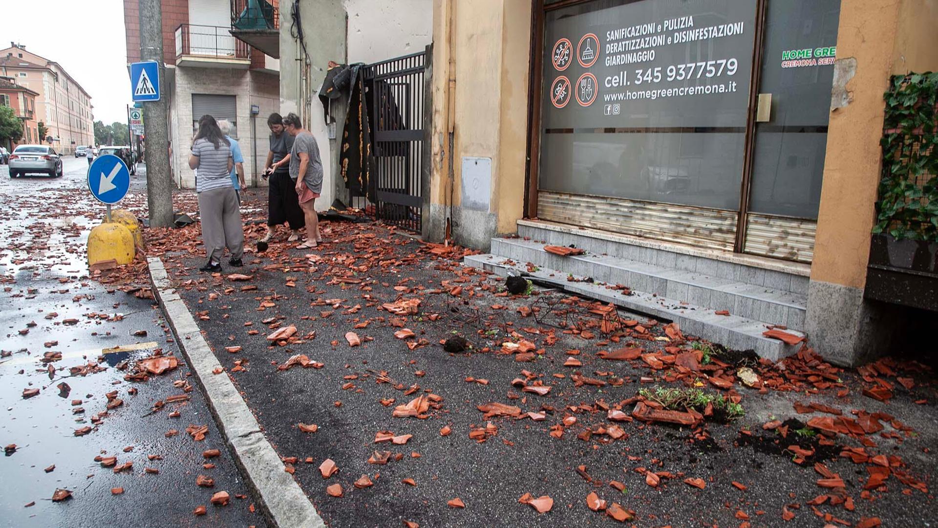 Cremona, Norditalien: Menschen stehen am Rand einer Straße zwischen zertrümmerten Dachziegeln.