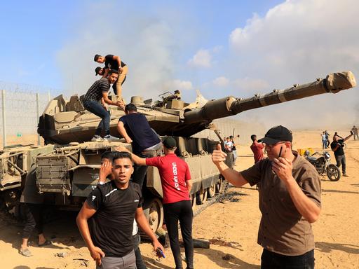 Palästinenser übernehmen die Kontrolle über einen israelischen Panzer, nachdem sie am Samstag, dem 7. Oktober 2023, den Grenzzaun zu Israel von Khan Yunis im südlichen Gazastreifen aus überquert haben. 
