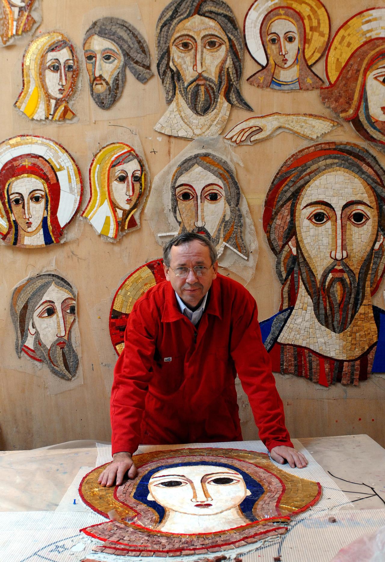 Marko Rupnik steht vor Entwürfen seiner Mosaiken mit Heiligenfiguren im byzantinischen Stil