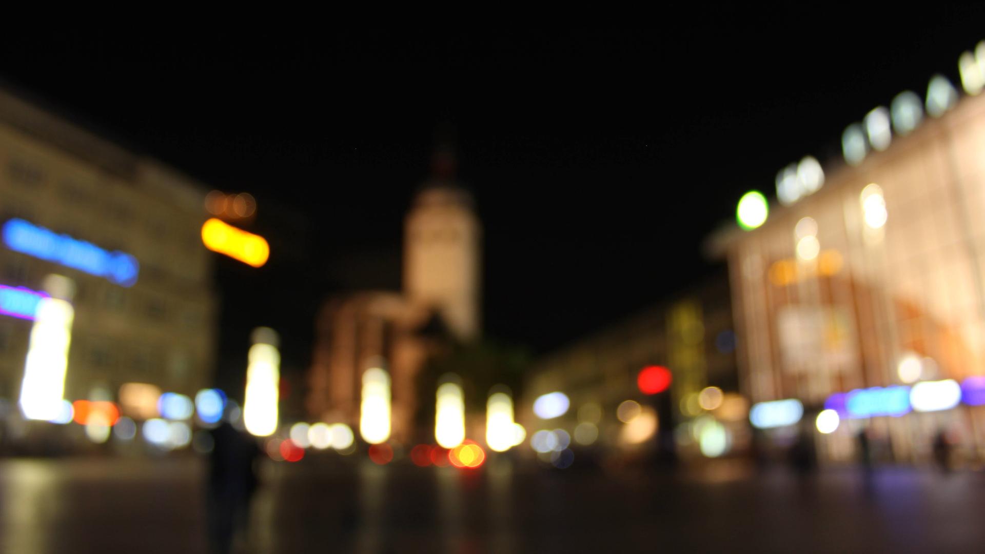 Ein verschwommen fotografierte Straßenszene in der Nacht mit bunten Lichtflecken. 