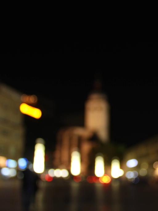 Ein verschwommen fotografierte Straßenszene in der Nacht mit bunten Lichtflecken. 