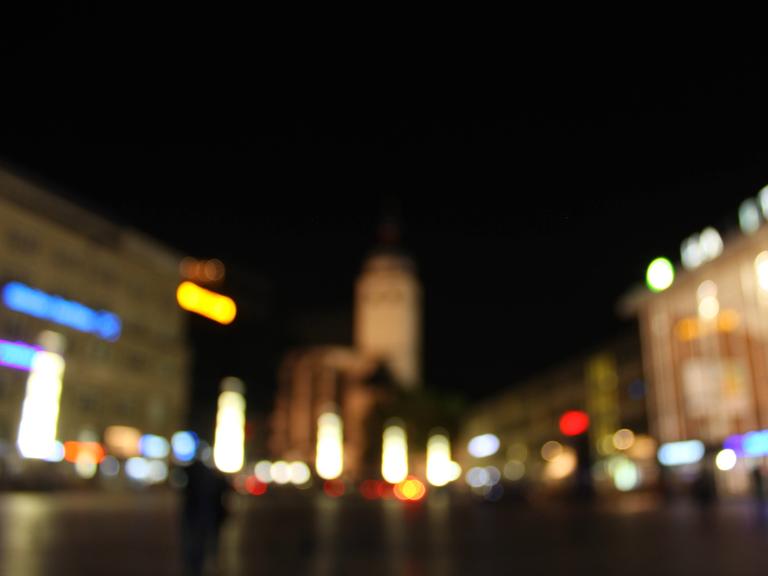 Ein verschwommen fotografierte Straßenszene in der Nacht mit bunten Lichtflecken. 