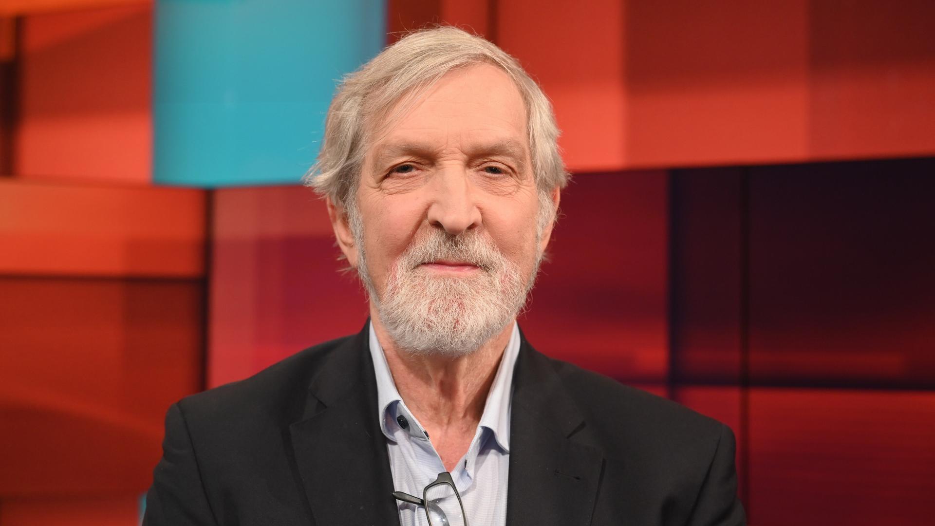 Shimon Stein sitzt in einem Fernsehstudio mit rot gekacheltem Hintergrund Shimon Stein sitzt in einem Fernsehstudio mit rot gekacheltem Hintergrund