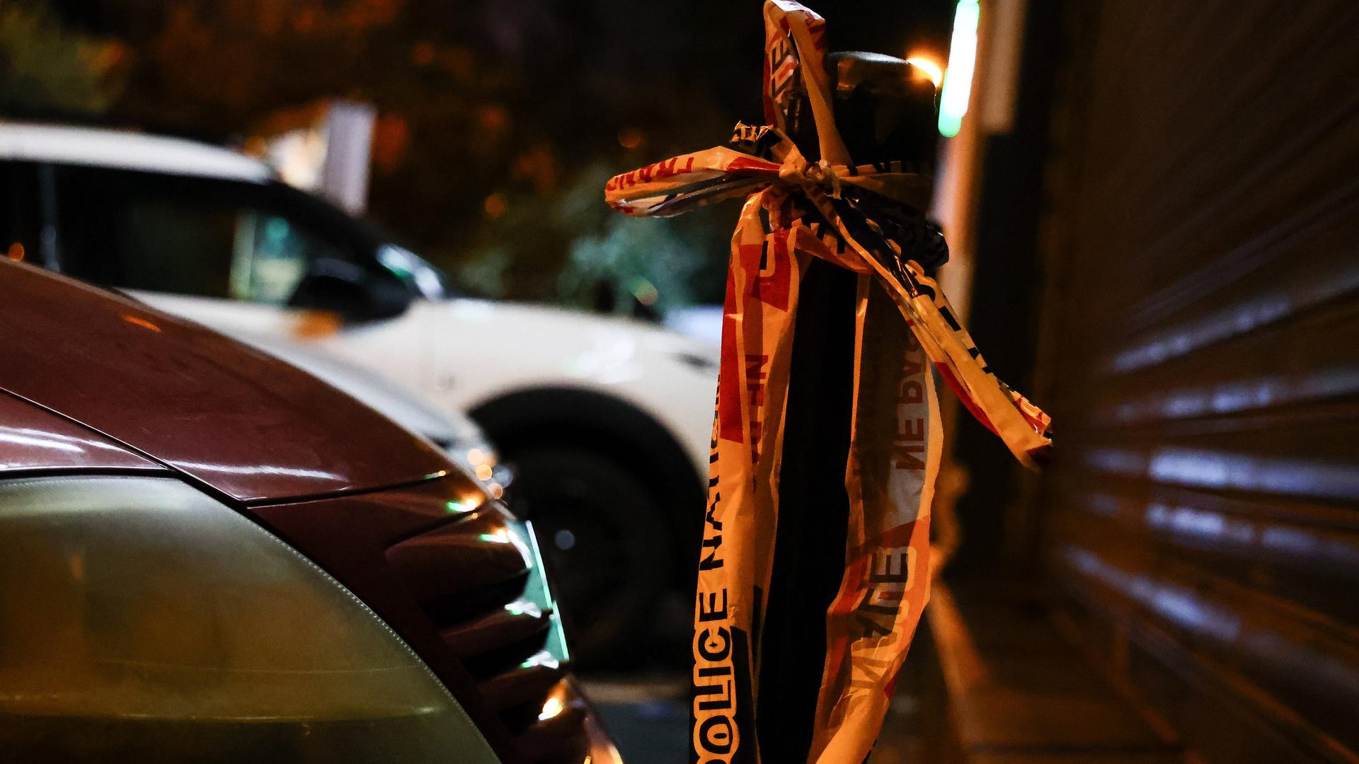 Ein Flatterband der französischen Polizei hängt an einem Straßenpoller.