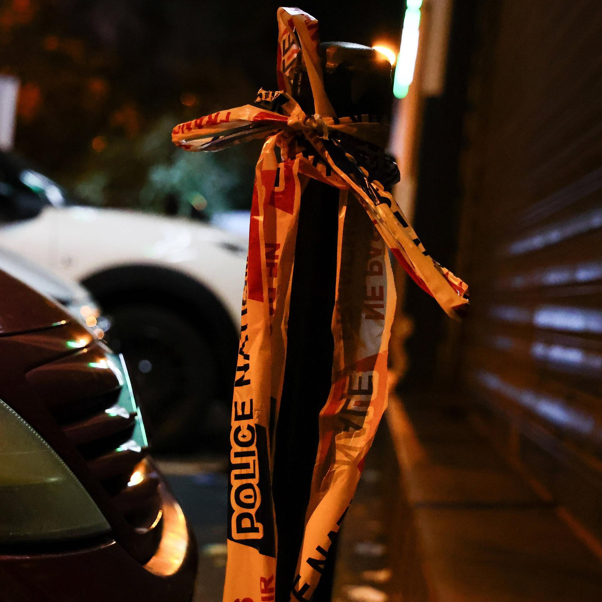Ein Flatterband der französischen Polizei hängt an einem Straßenpoller.