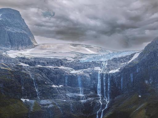 Das Wasser von einem schmelzenden Gletscher in Norwegen läuft an den Felswänden herab.