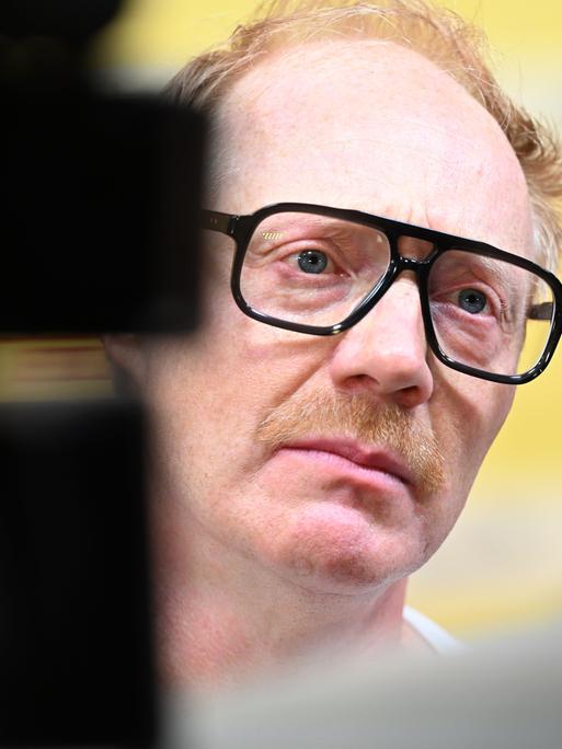 Simon Schwarz mit schwarzer Hornbritte Brille in Nahaufnahme bei der Premiere des Films "Steckerlfischfiasko" 