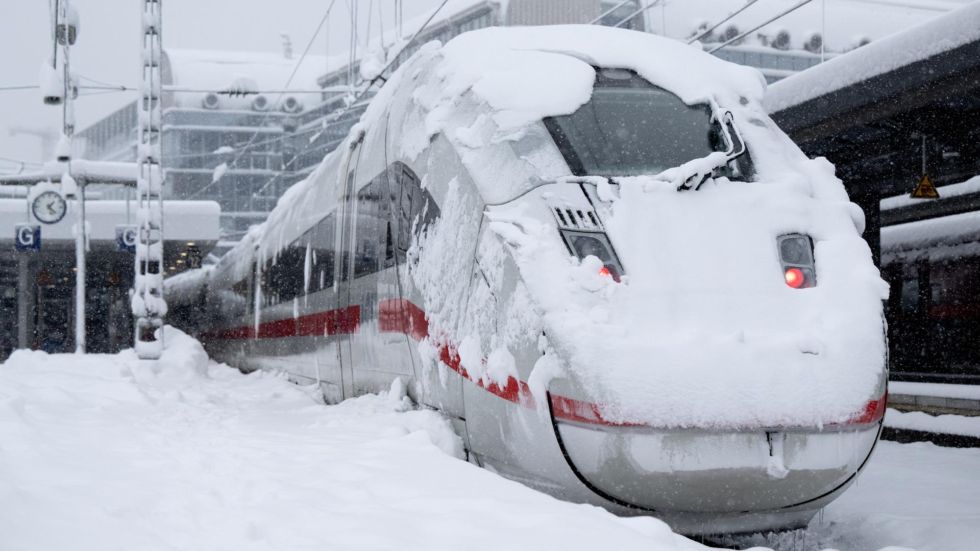 Ein eingeschneiter ICE der Deutschen Bahn (DB) steht auf einem verschneiten Gleis am Hauptbahnhof München.