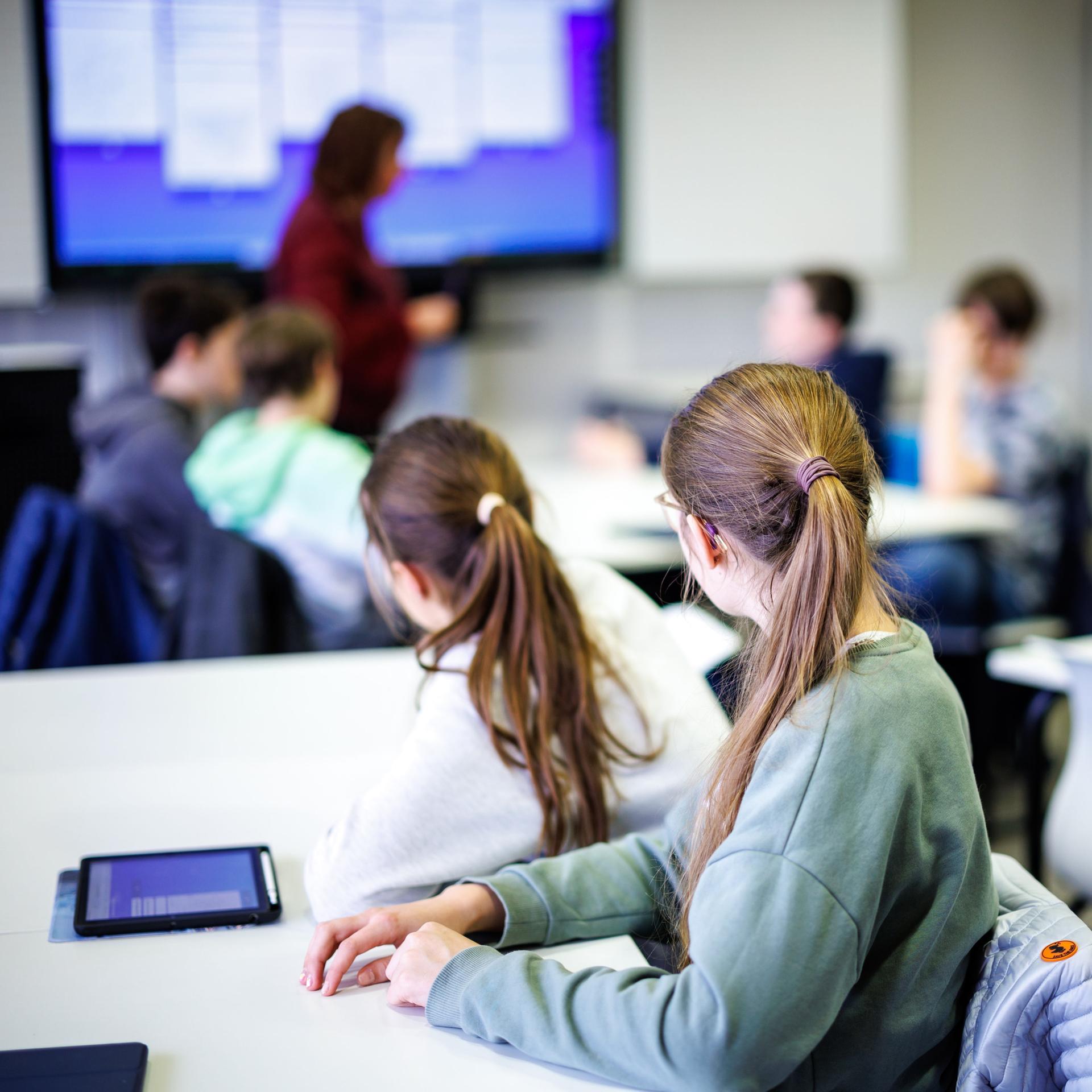 Schüler einer siebten Klasse hören in einem Klassenraum im Fach Mathe ihrer Lehrerin zu.