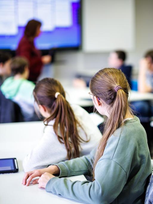 Schüler einer siebten Klasse hören in einem Klassenraum im Fach Mathe ihrer Lehrerin zu.