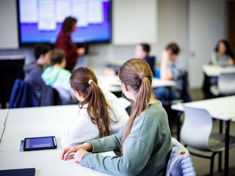 Schüler einer siebten Klasse hören in einem Klassenraum im Fach Mathe ihrer Lehrerin zu.