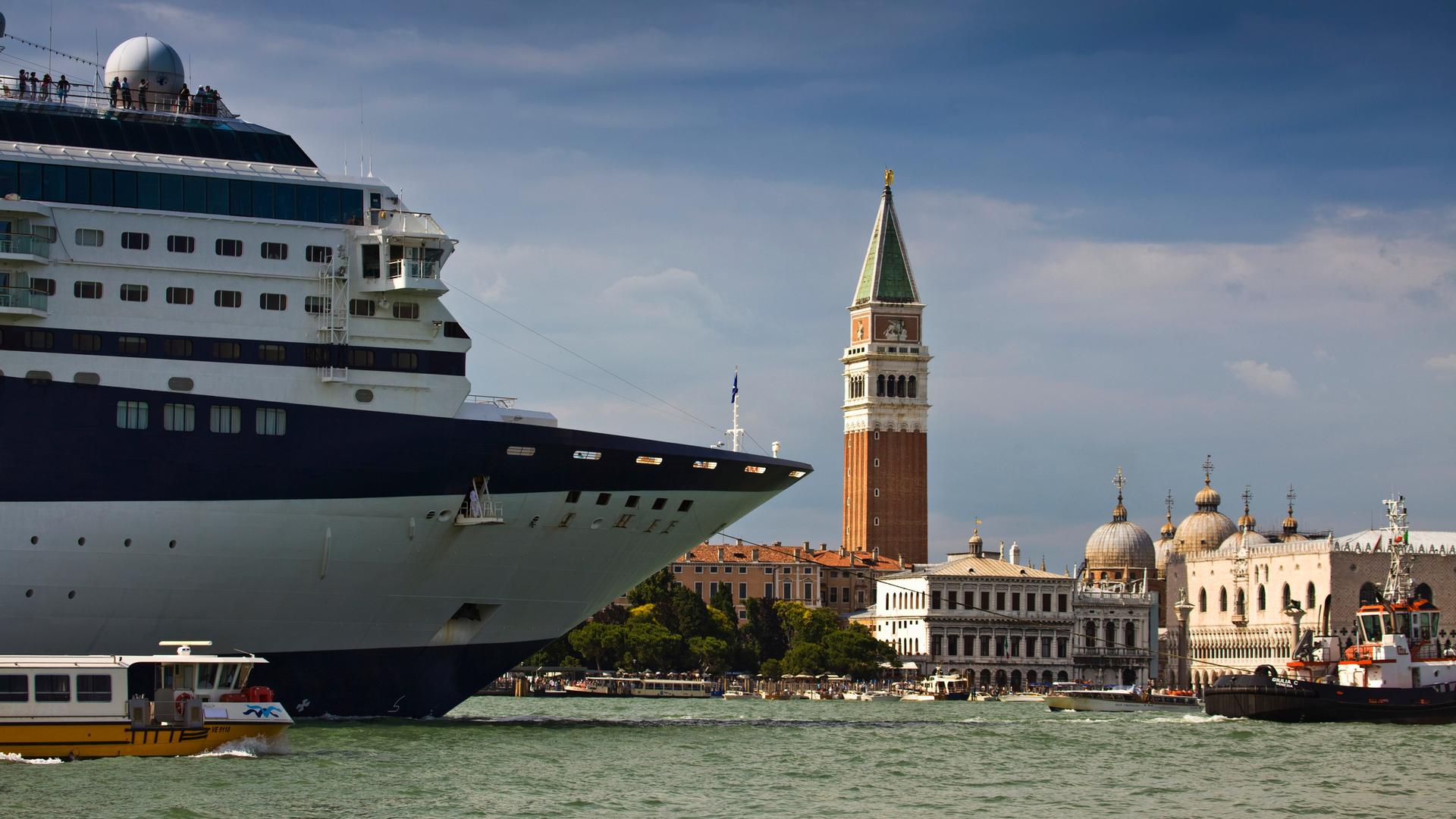 Ein Kreuzfahrtschiff in Venedig. Daneben ein kleines Boot.