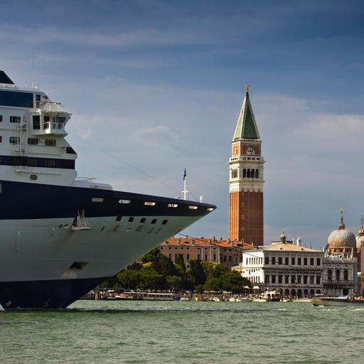 Ein Kreuzfahrtschiff in Venedig. Daneben ein kleines Boot.