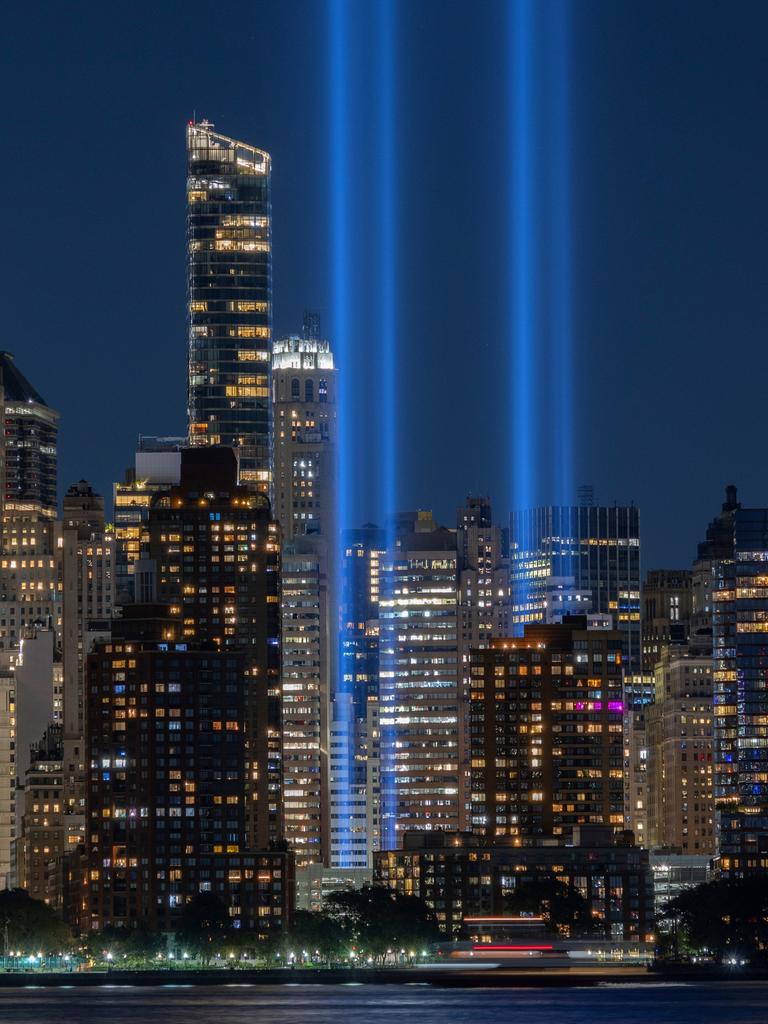 Zwei blaue Lichtsäulen ragen zwischen den Hochhäusern von New York bei Nacht in die Luft.