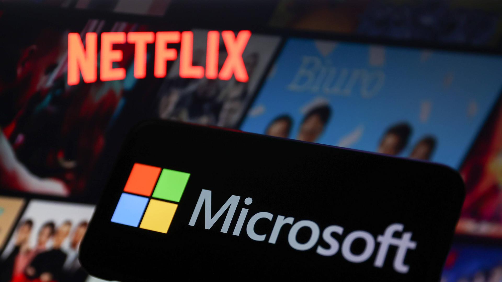 Das Netflix-Logo schwebt neben dem Microsoft-Logo über einer Auswahl von Filmen und Serien auf einem Bildschirm. Das Netflix-Logo schwebt neben dem Microsoft-Logo über einer Auswahl von Filmen und Serien auf einem Bildschirm.