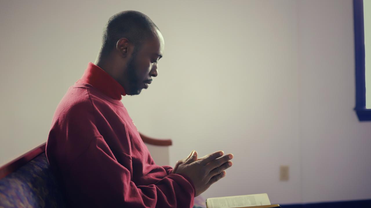 Eine afroamerikanische Person betet in einer Kirche in den USA.