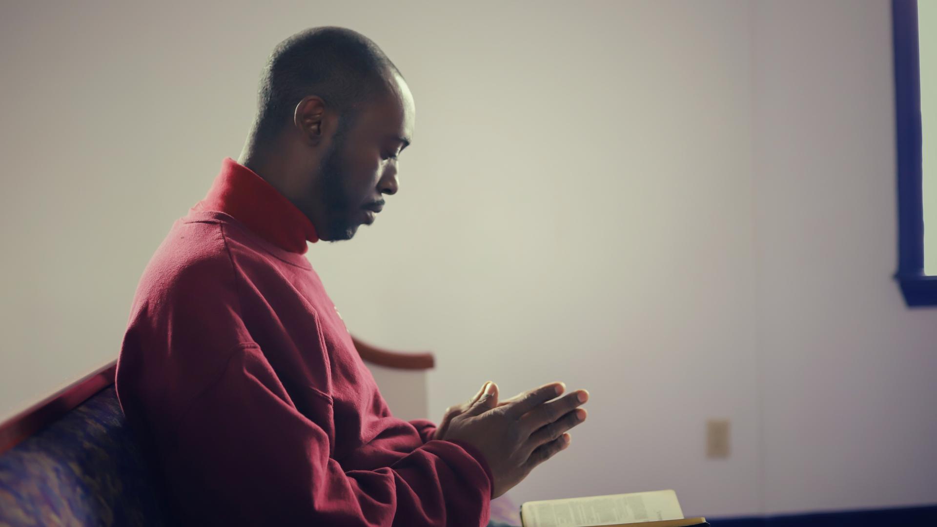 Eine afroamerikanische Person betet in einer Kirche in den USA.