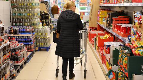 Eine Frau schiebt einen Einkaufswagen durch einen Discounter.