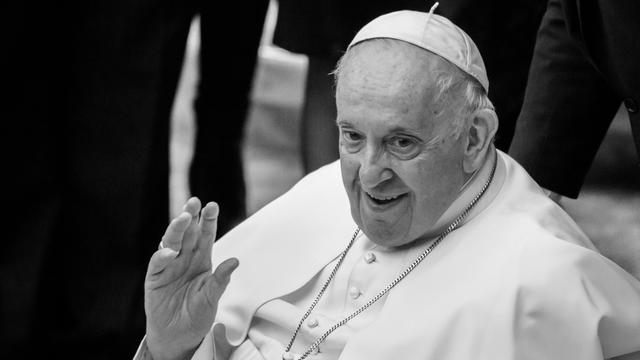 Der Papst lächelt. Er winkt in Richtung der Kamera. 