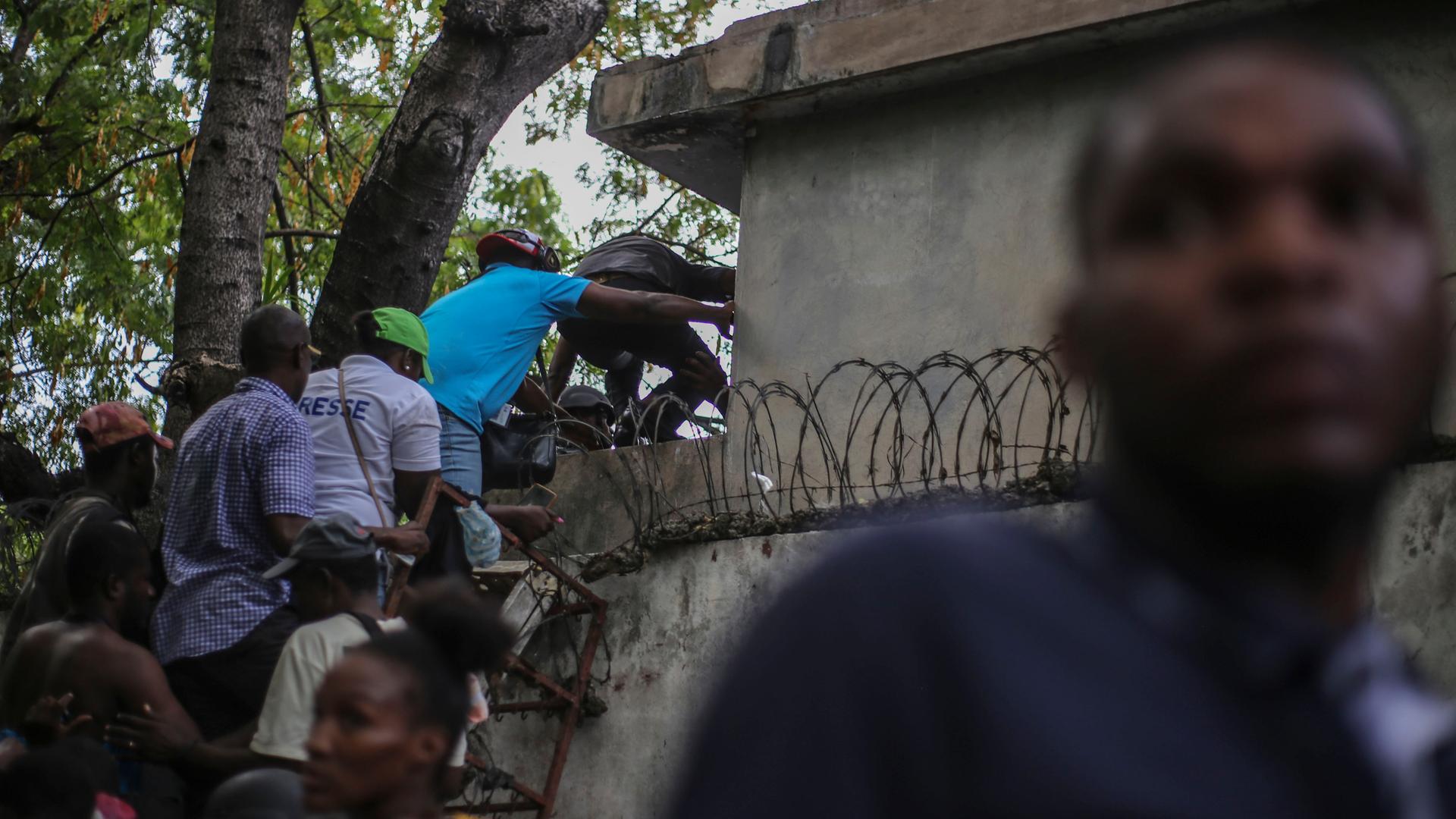 Journalisten klettern auf eine Mauer, um sich vor Schüssen zu schützen, nachdem sie von bewaffneten Banden im Allgemeinen Krankenhaus in Port-au-Prince, Haiti, beschossen wurden. Journalisten klettern auf eine Mauer, um sich vor Schüssen zu schützen, nachdem sie von bewaffneten Banden im Allgemeinen Krankenhaus in Port-au-Prince, Haiti, beschossen wurden.