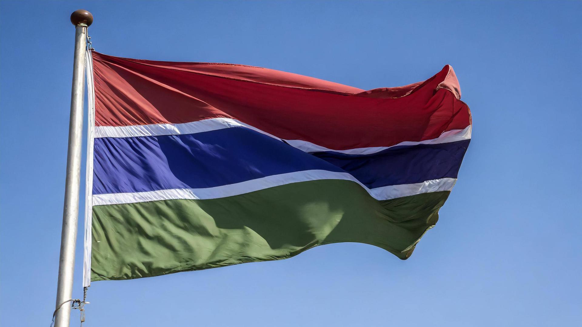 Die Fahne von Gambia flattert im Wind bei blauem Himmel. Die Fahne von Gambia flattert im Wind bei blauem Himmel.