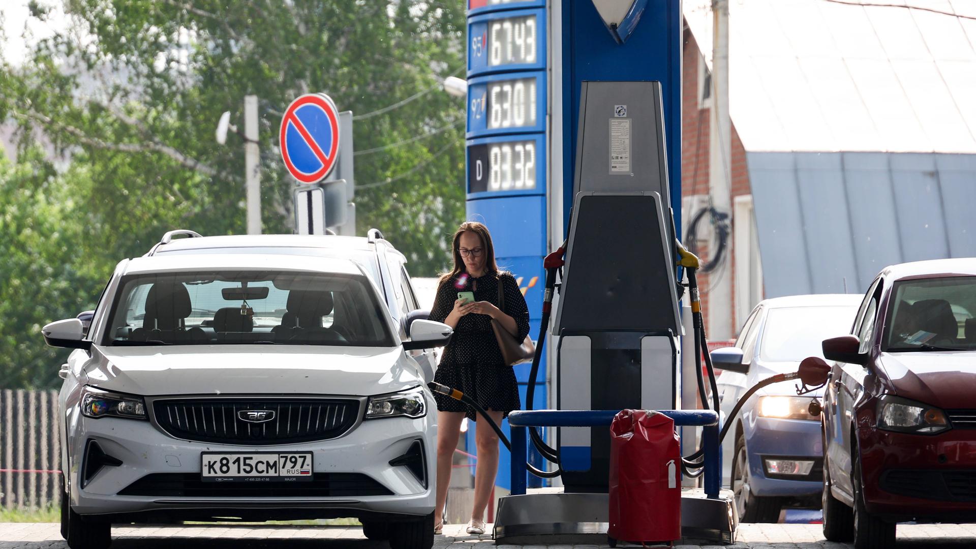 An einer Tankstelle in Russland steht eine Frau an einer Zapfsäule und tankt ihr Fahrzeug. 