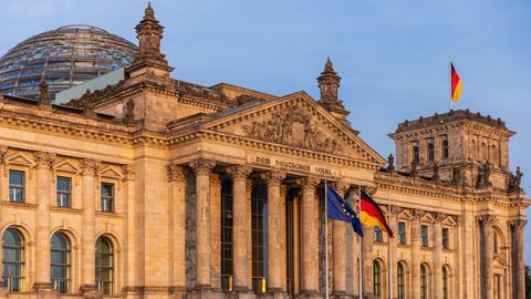 Die deutsche und die europäische Flagge wehen vor dem Reichstagsgebäude in Berlin.