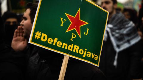 Demonstranten mit einem grünen Schild, auf dem steht "Defend Rokava".